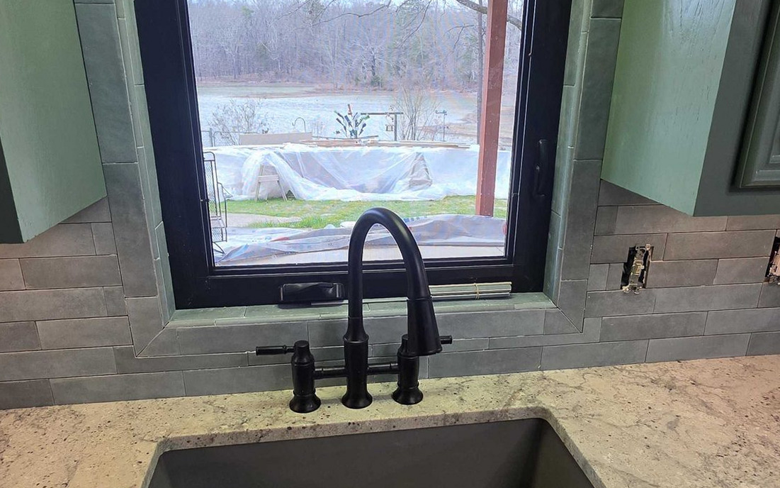 New sink and faucet set into a stone counter under a kitchen window